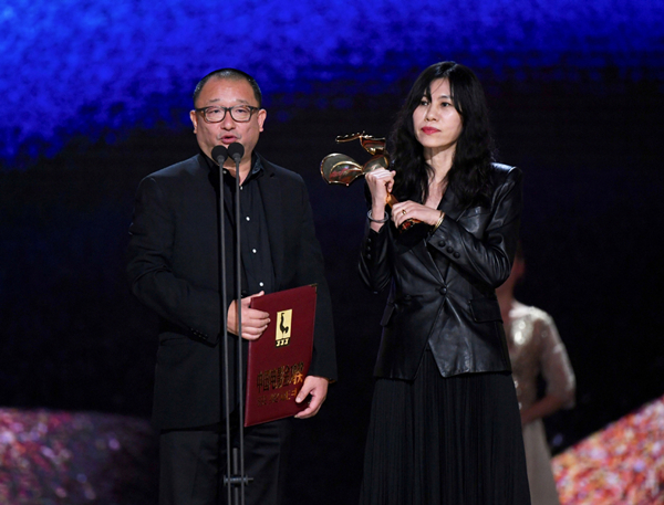 Wang Xiaoshuai and A Mei take the best screenplay award for So Long, My Son at the Golden Rooster Awards in Xiamen, Fujian province, on Nov 23. [Photo/Xinhua]
